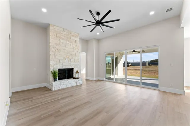 an empty room with wooden floor a ceiling fan and windows