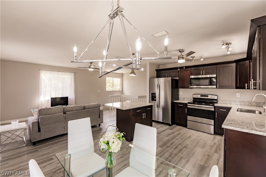 8049 Albatross Road Fort Myers, FL 33967 - Photo 1 of 35 a large kitchen with stainless steel appliances kitchen island granite countertop a refrigerator a stove a sink dishwasher and a dining table with the living room view