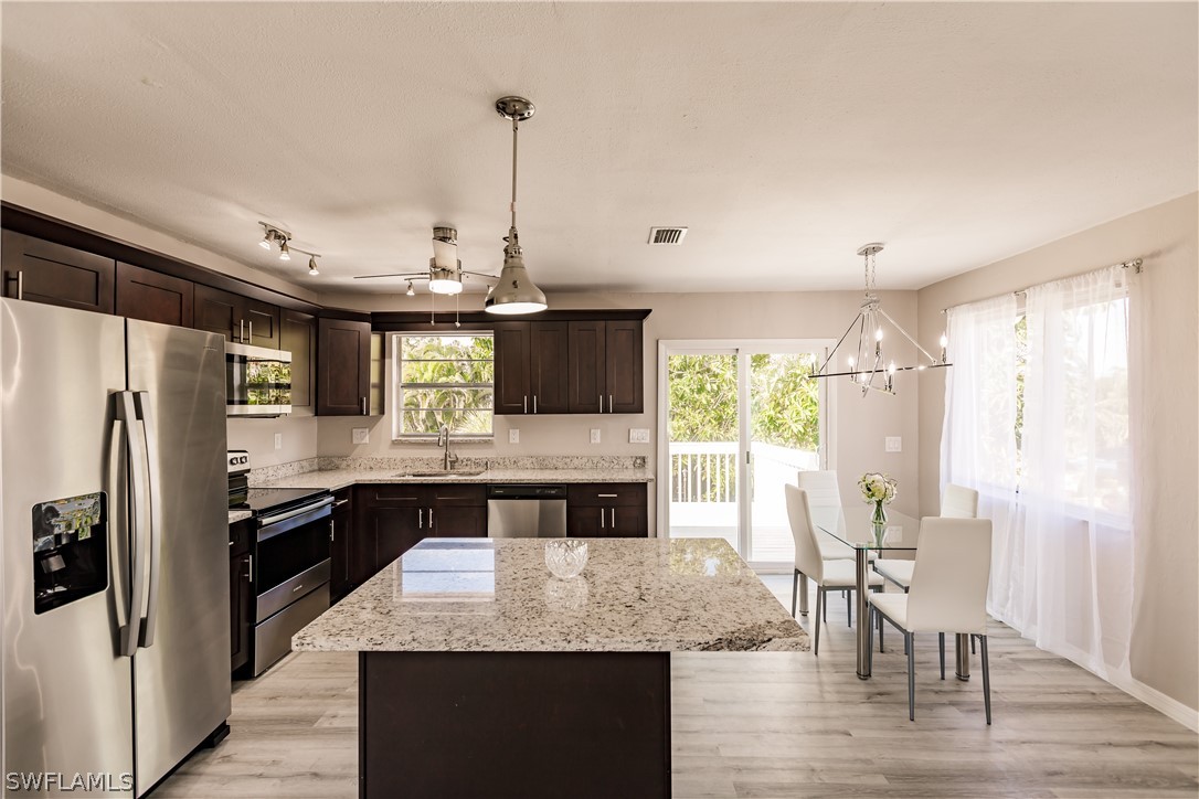 8049 Albatross Road Fort Myers, FL 33967 - Photo 23 of 35 a kitchen with kitchen island granite countertop a stove and refrigerator