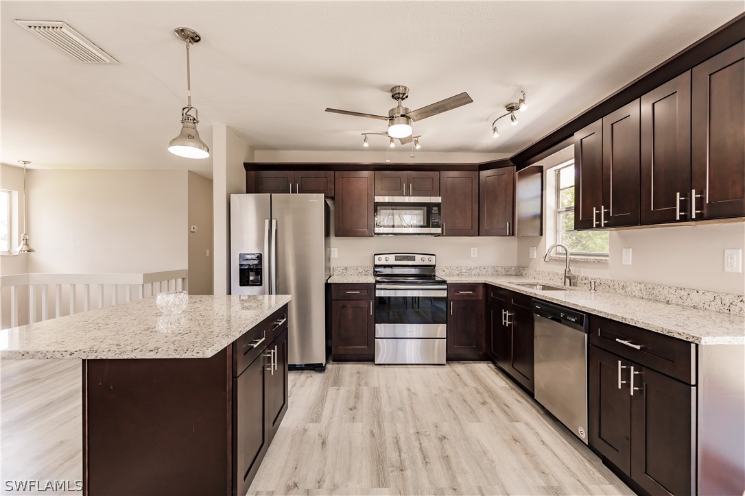 8049 Albatross Road Fort Myers, FL 33967 - Photo 24 of 35 a kitchen with stainless steel appliances granite countertop a refrigerator a sink dishwasher a stove oven and a dining table with wooden floor