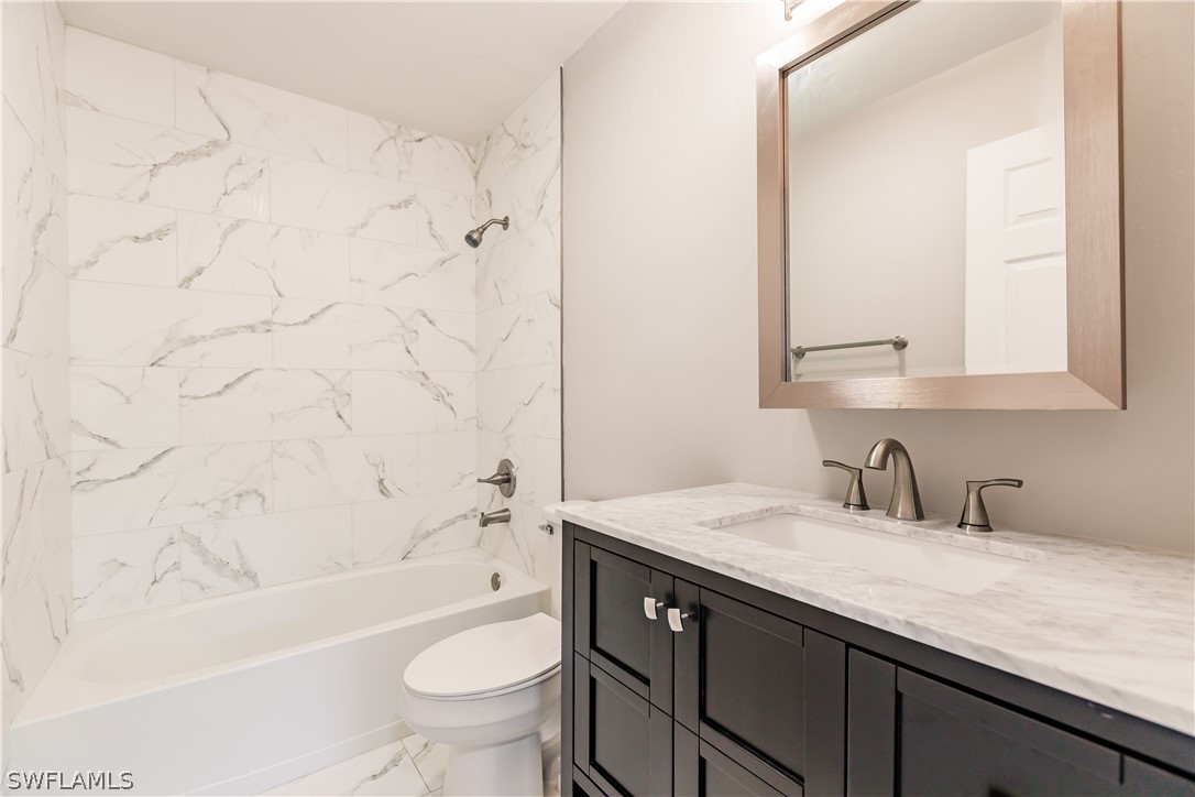 8049 Albatross Road Fort Myers, FL 33967 - Photo 27 of 35 a bathroom with a granite countertop sink a toilet and a bathtub