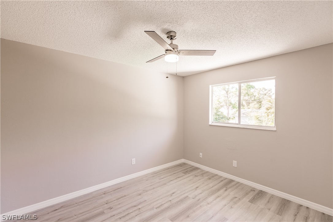 8049 Albatross Road Fort Myers, FL 33967 - Photo 28 of 35 an empty room with wooden floor ceiling fan and windows