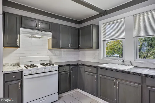 a kitchen with granite countertop a sink stove and cabinets