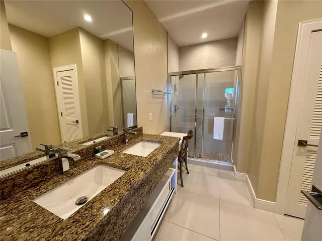 a bathroom with a granite countertop sink a mirror and a shower