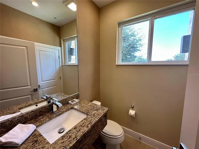 a bathroom with a granite countertop sink toilet and mirror