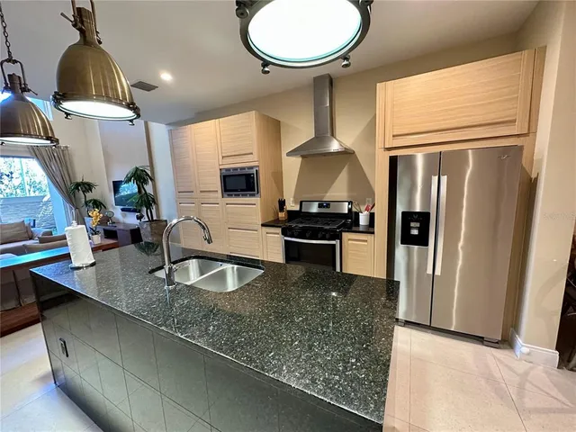 a kitchen with granite countertop a sink a counter space and stainless steel appliances