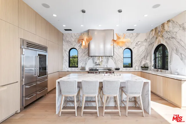 a kitchen with stainless steel appliances kitchen island granite countertop a stove a sink a dining table and chairs