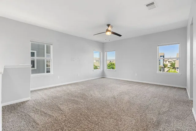 an empty room with windows and fan