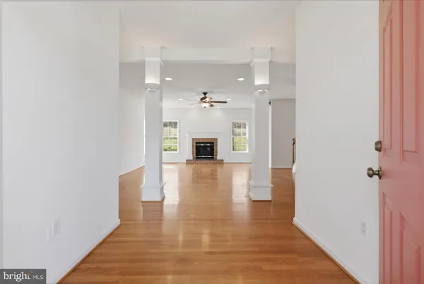 an empty room with wooden floor fireplace and windows