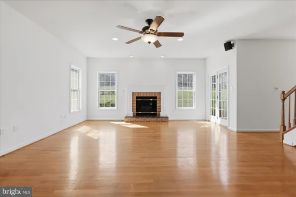 a view of an empty room with wooden floor fireplace and a window