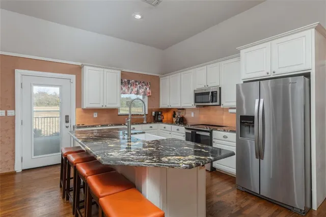 a kitchen with stainless steel appliances granite countertop a refrigerator stove top oven and sink