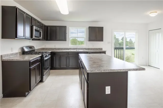 a kitchen with stainless steel appliances granite countertop a stove a sink and a microwave