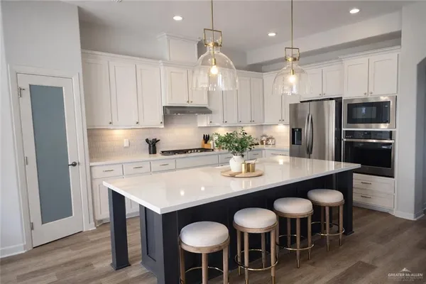 a kitchen with stainless steel appliances granite countertop a dining table chairs refrigerator and microwave