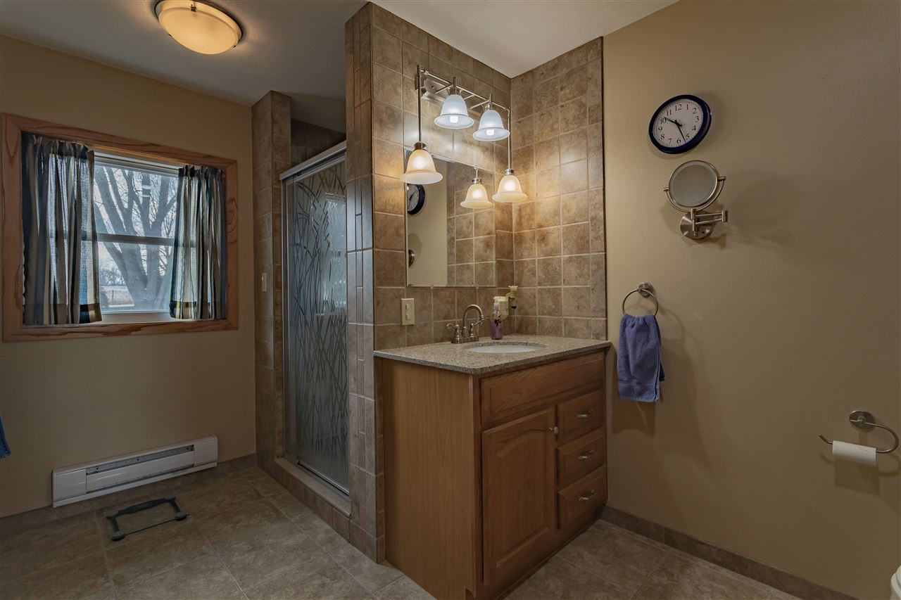 9119 Montague Road Winnebago, IL 61088 - Photo 20 of 36 a bathroom with a granite countertop sink a mirror and shower