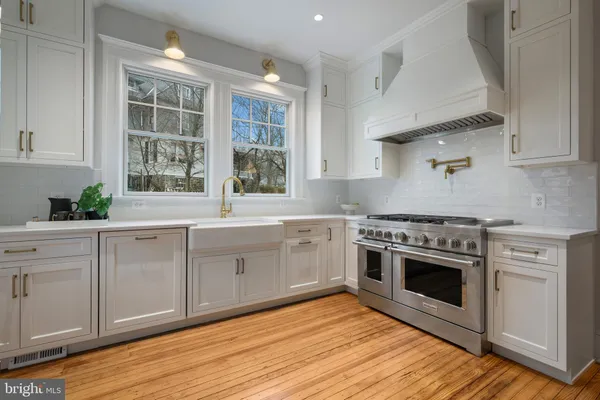 a kitchen with stainless steel appliances white cabinets and wooden floors