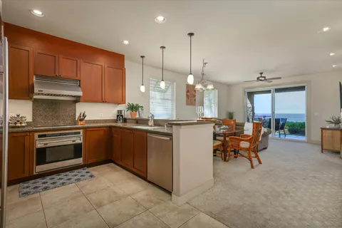 a kitchen with stainless steel appliances granite countertop a stove top oven a sink dishwasher a dining table and chairs with wooden floor