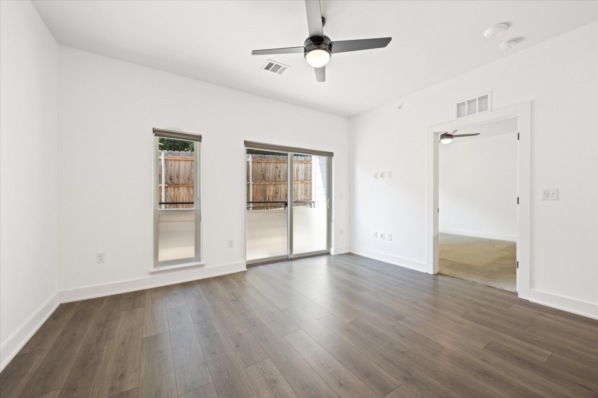 2220 Webberville Road, Unit 216 Austin, TX 78702 - Photo 10 of 26 Spacious room with wood-finish flooring, white baseboards, and a modern ceiling fan with integrated lighting