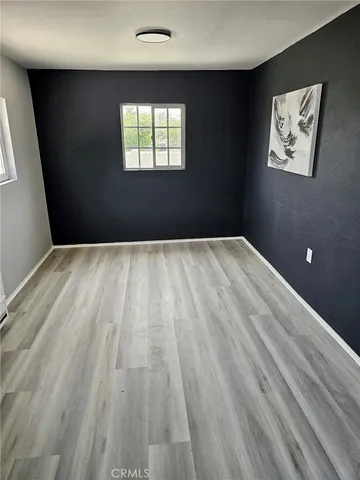 a view of an empty room with wooden floor and window