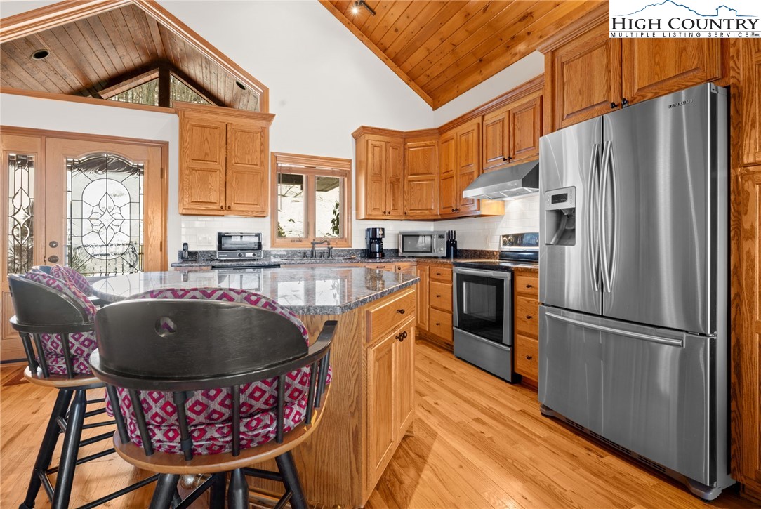 295 Supreme Golden Road Banner Elk, NC 28604 - Photo 13 of 40 a kitchen with stainless steel appliances granite countertop a refrigerator a sink dishwasher a stove and a dining table with wooden cabinet