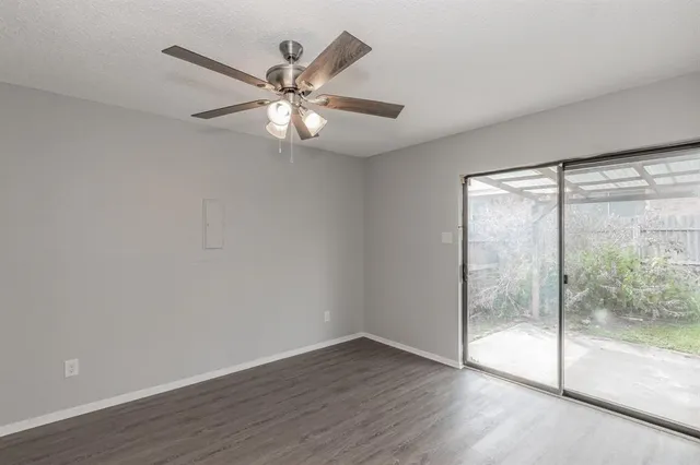 an empty room with wooden floor fan and windows