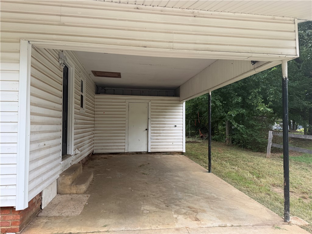 909 Riddell Street Clarksville, AR 72830 - Photo 3 of 26 Covered carport with concrete flooring, supported by metal posts