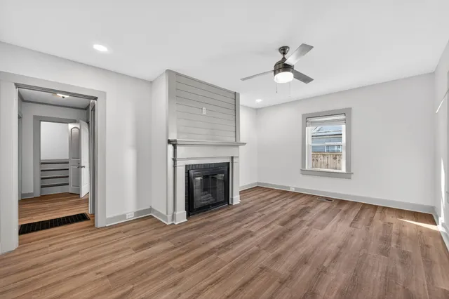 an empty room with wooden floor fireplace and windows