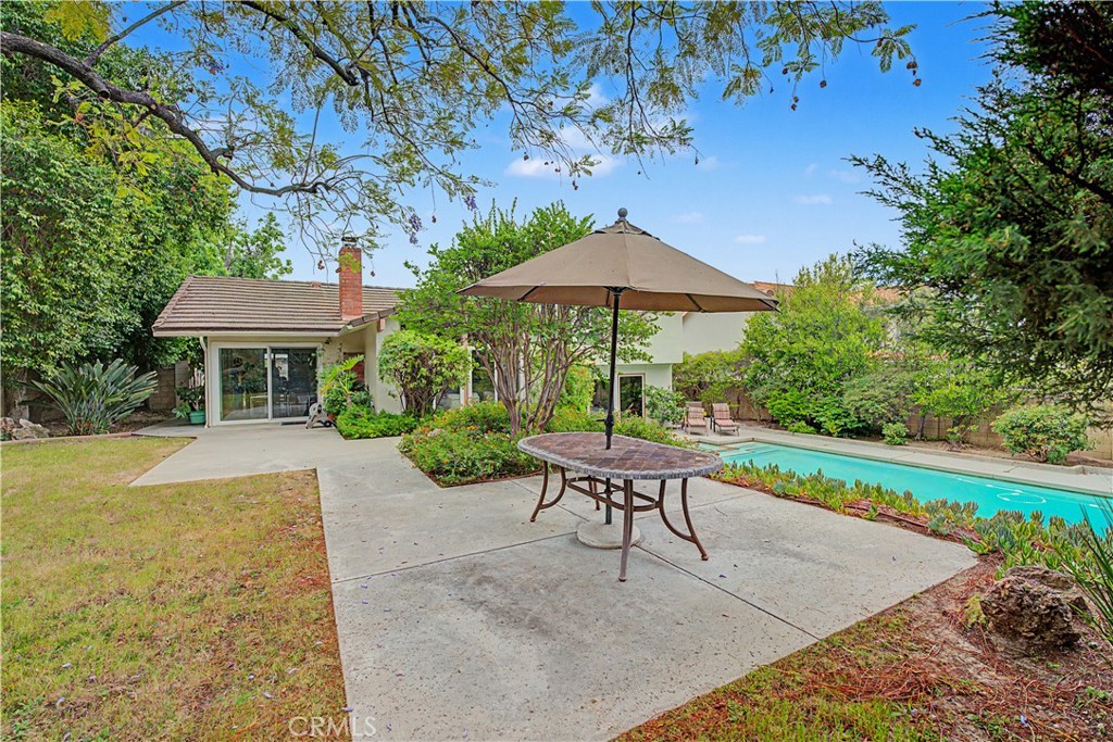 22671 Town Crier Road Calabasas, CA 91302 - Photo 8 of 35 a patio with a table and chairs under an umbrella