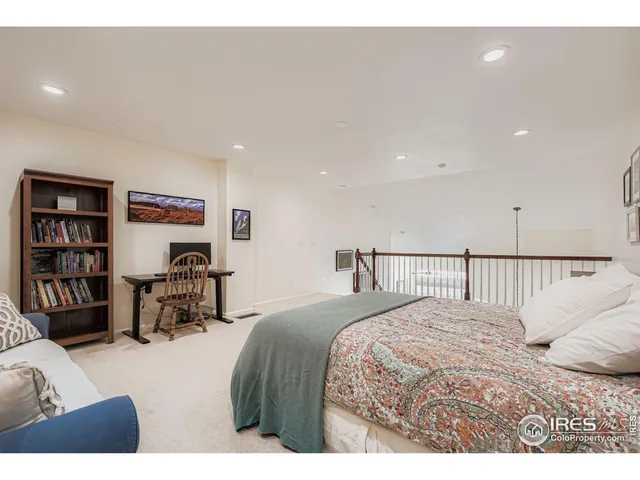 a bedroom with a bed a table and a bookshelf with wooden floor