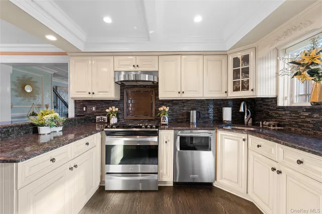 a kitchen with stainless steel appliances granite countertop a stove a sink and white cabinets