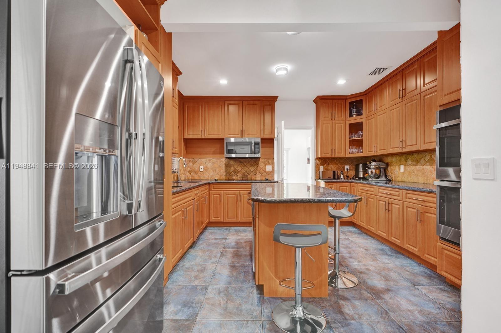 3757 Prairie Avenue Miami Beach, FL 33140 - Photo 7 of 19 a kitchen with stainless steel appliances granite countertop a refrigerator and a stove top oven