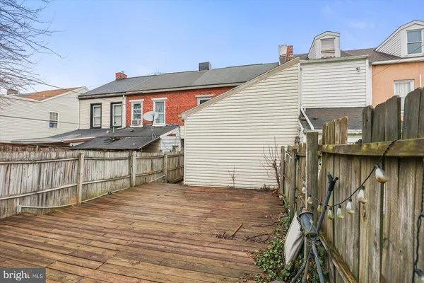 a view of a backyard with large trees and wooden fence