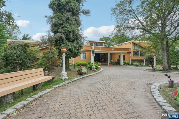 a front view of a house with a garden and trees