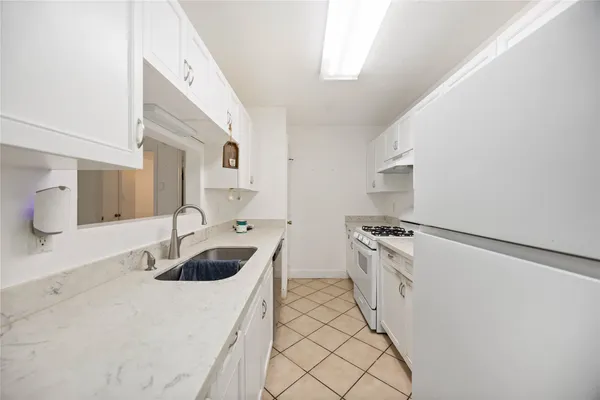 a kitchen with granite countertop a sink and a stove with white countertops