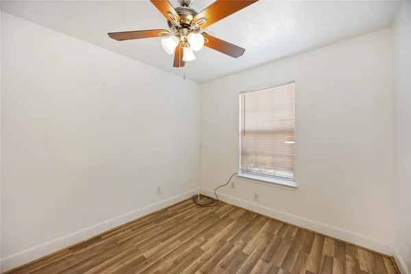 an empty room with a window and ceiling fan