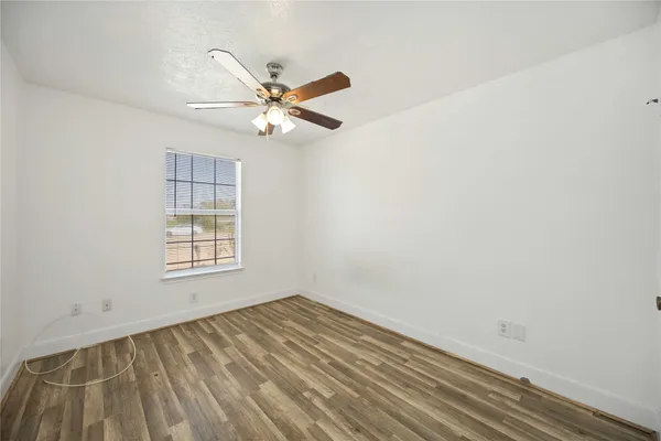an empty room with wooden floor fan and windows