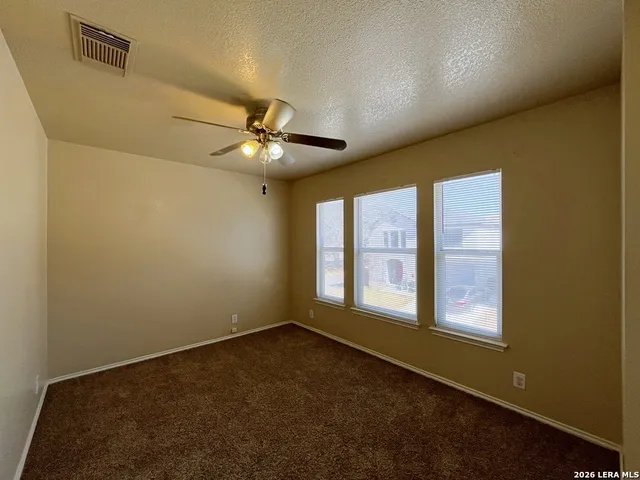 an empty room with windows and fan