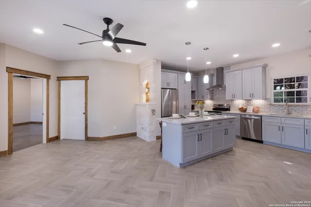 a kitchen with stainless steel appliances kitchen island granite countertop a stove a sink a refrigerator and chairs