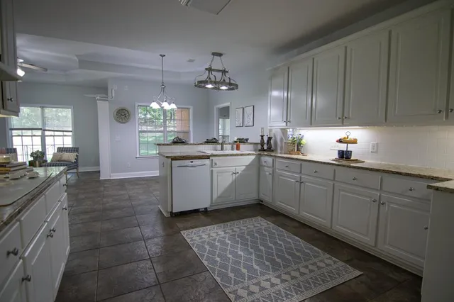 a kitchen with granite countertop a sink window and cabinets
