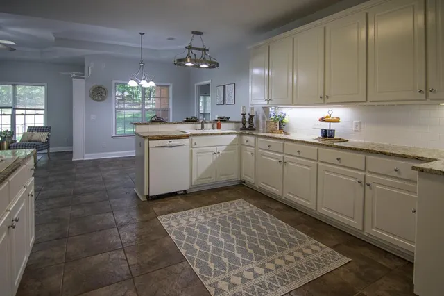 an empty room with chandelier fan and windows
