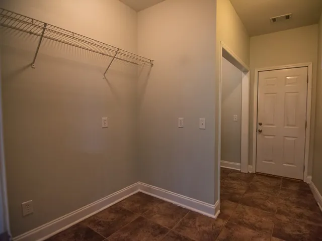 an empty room with windows and chandelier fan