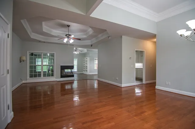 a view of an empty room with wooden floor and a chandelier
