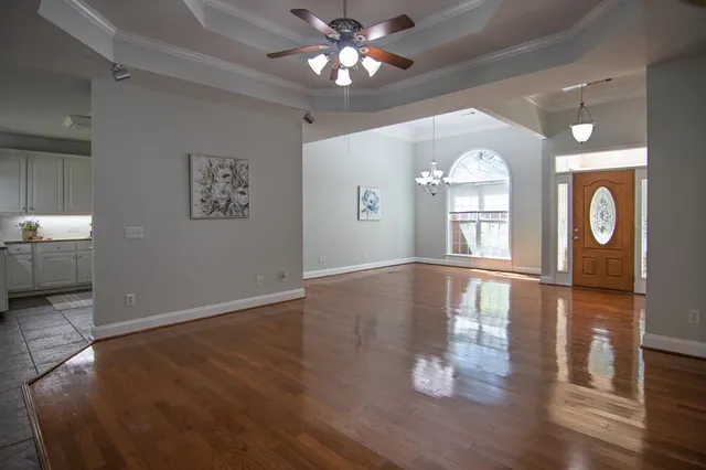 an empty room with wooden floor chandelier and windows