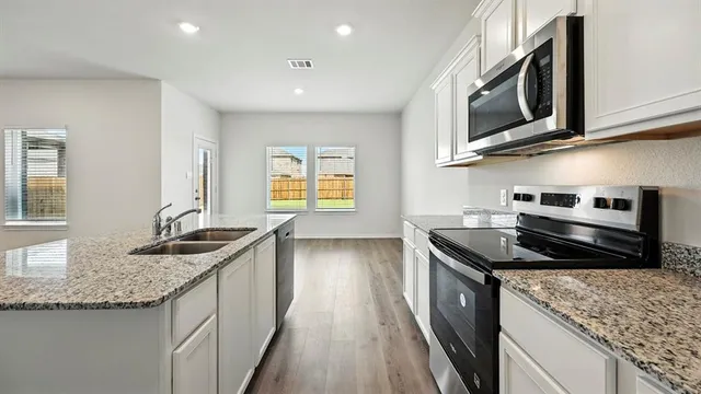 a kitchen with granite countertop a refrigerator and a stove top oven