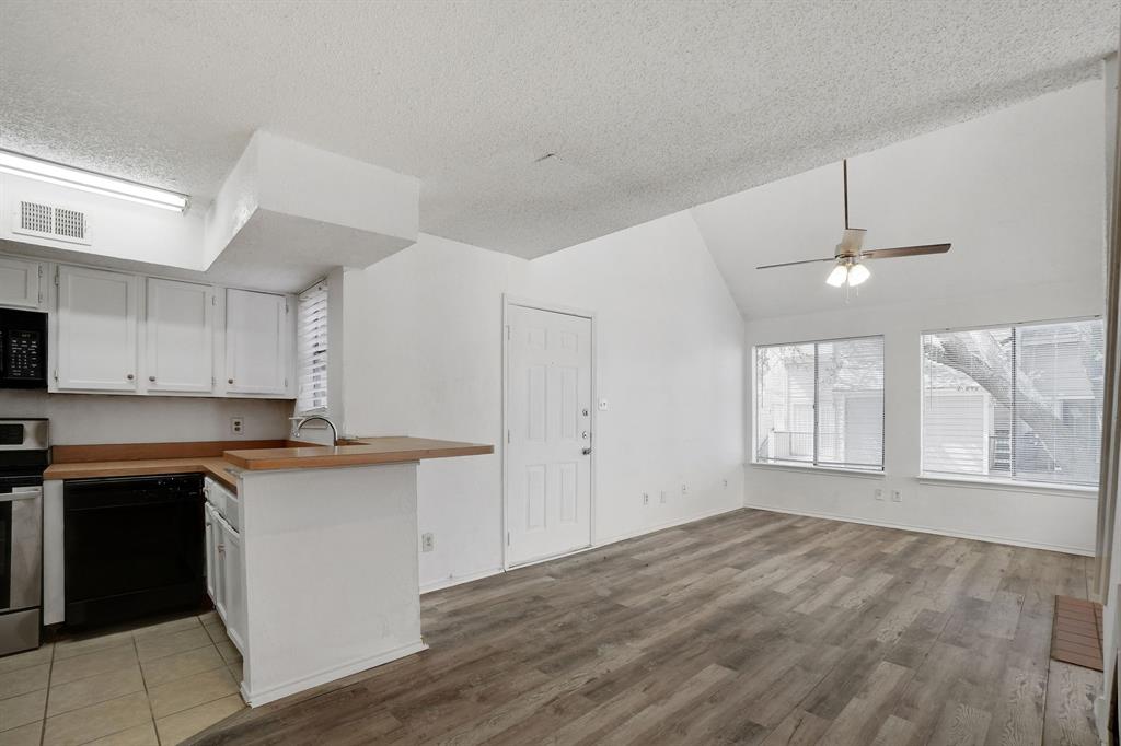 9821 Walnut Street, Unit 204 Dallas, TX 75243 - Photo 11 of 32 a kitchen with granite countertop a stove a sink and white cabinets with wooden floor