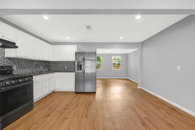 a kitchen with stainless steel appliances granite countertop a refrigerator a stove and a wooden floors