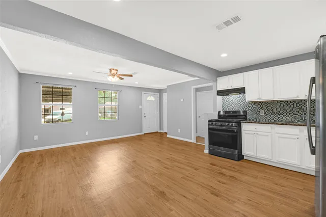 a view of empty room with kitchen and window