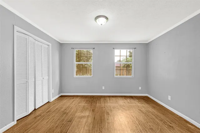 an empty room with wooden floor and windows