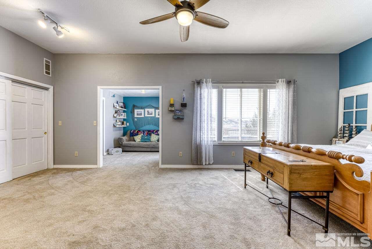 15555 Pyramid Way Reno, NV 89510 - Photo 29 of 39 a spacious bedroom with a bed and a chandelier