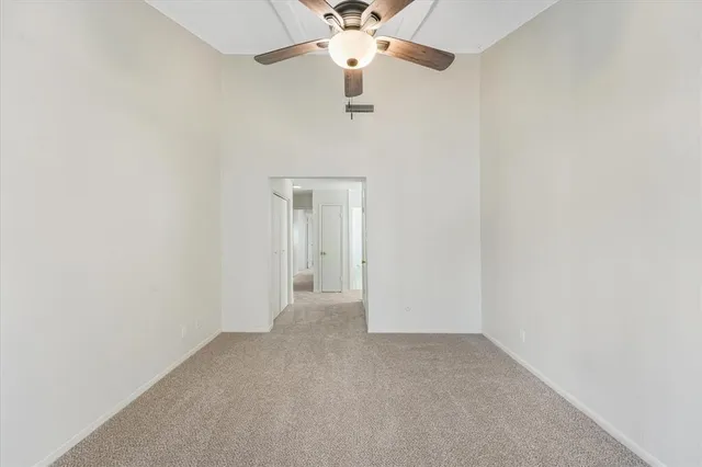 an empty room with a chandelier fan and a ceiling fan