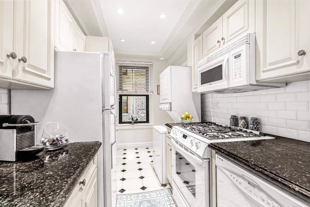 135 East 74th Street, Unit 6C Manhattan, NY 10021 - Photo 4 of 8 a kitchen with granite countertop a sink stove and cabinets